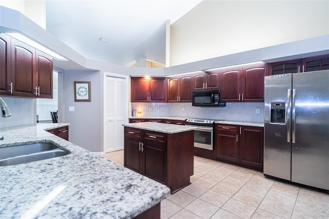 kitchen featuring stainless steel appliances, light tile patterned floors, a sink, and decorative backsplash