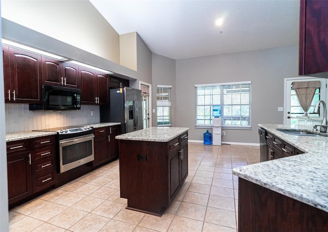 kitchen with a kitchen island, light tile patterned flooring, a sink, stainless steel appliances, and backsplash