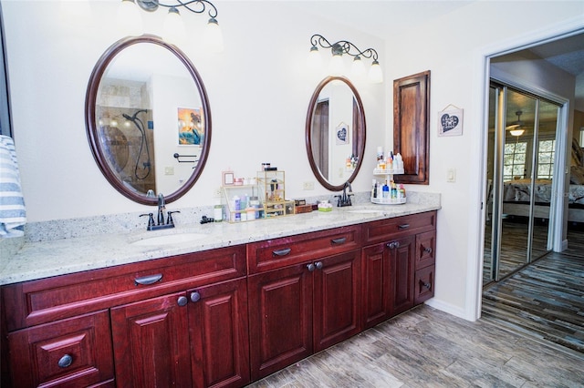 ensuite bathroom with wood finished floors, double vanity, a sink, and connected bathroom