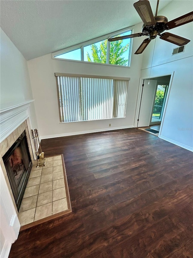 7444 Candlelight Ct, New Port Richey, FL 34652 - unfurnished living room with vaulted ceiling, ceiling fan, a tile fireplace, a textured ceiling, and wood finished floors