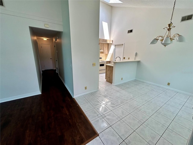 7444 Candlelight Ct, New Port Richey, FL 34652 - unfurnished living room featuring high vaulted ceiling, a chandelier, and a skylight