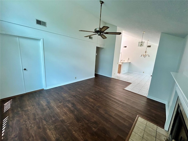 7444 Candlelight Ct, New Port Richey, FL 34652 - unfurnished living room with a ceiling fan, wood finished floors, high vaulted ceiling, a chandelier, and a textured ceiling