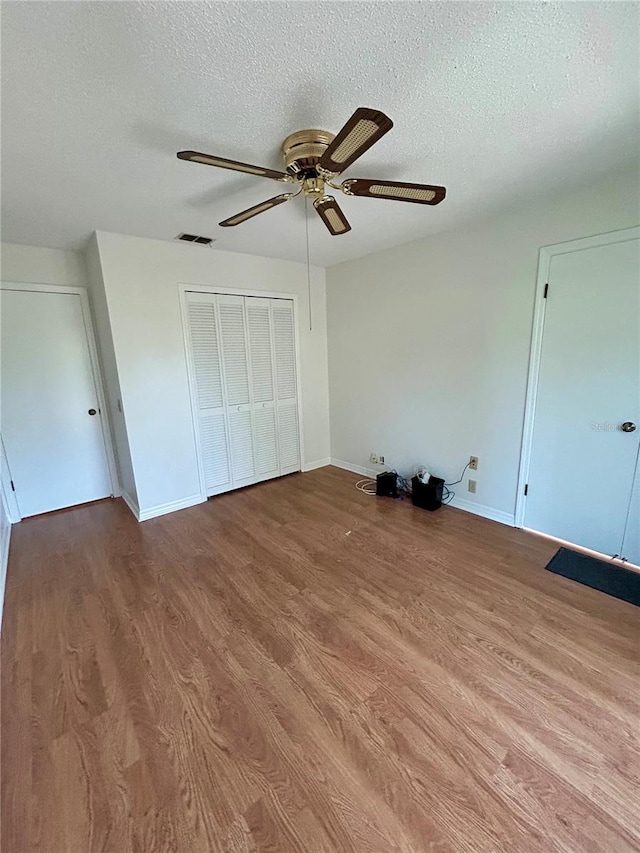 7444 Candlelight Ct, New Port Richey, FL 34652 - unfurnished bedroom featuring a textured ceiling, wood finished floors, a closet, and a ceiling fan
