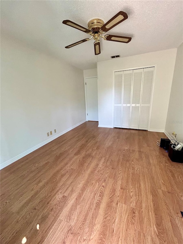 7444 Candlelight Ct, New Port Richey, FL 34652 - unfurnished bedroom with wood finished floors, a closet, a textured ceiling, and ceiling fan