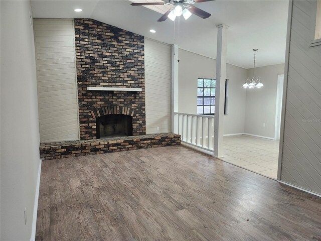 18232 Monteverde Dr, Spring Hill, FL 34610 - unfurnished living room with ceiling fan with notable chandelier, a brick fireplace, wood finished floors, and lofted ceiling