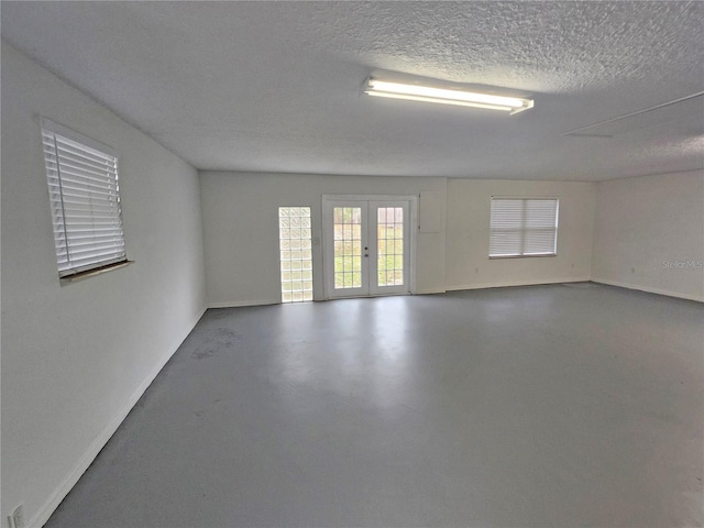 18232 Monteverde Dr, Spring Hill, FL 34610 - spare room with baseboards, french doors, a textured ceiling, and concrete flooring
