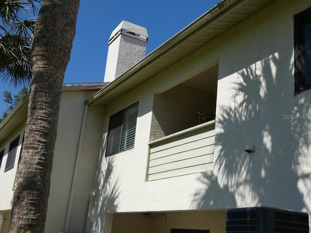 view of side of home with stucco siding and a chimney