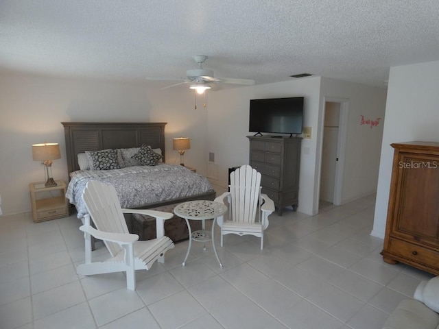 bedroom with visible vents, a textured ceiling, ceiling fan, and light tile patterned floors