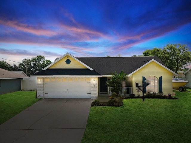 ranch-style house featuring a front lawn, driveway, an attached garage, fence, and brick siding
