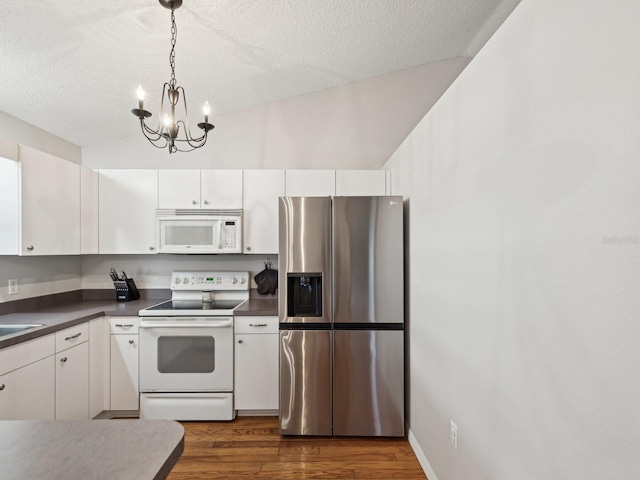 kitchen with dark countertops, dark wood-style floors, white cabinetry, and white appliances