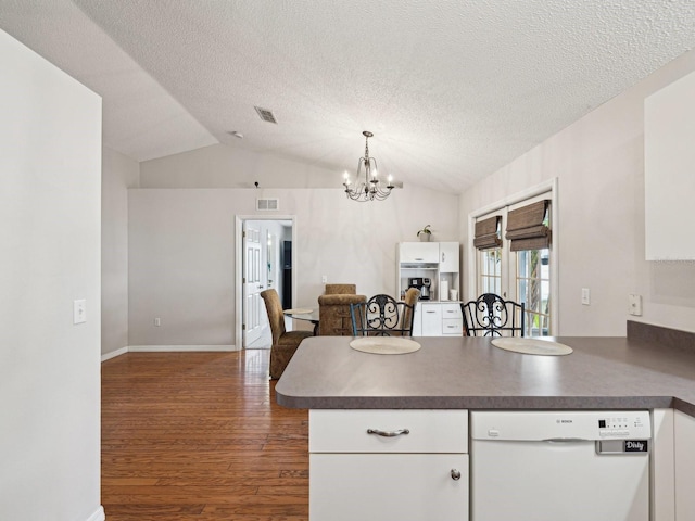 kitchen with visible vents, white dishwasher, dark wood-type flooring, a peninsula, and a chandelier