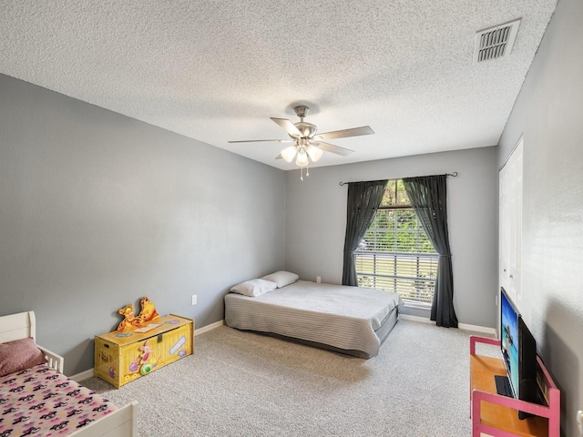carpeted bedroom featuring baseboards, a ceiling fan, a textured ceiling, and visible vents