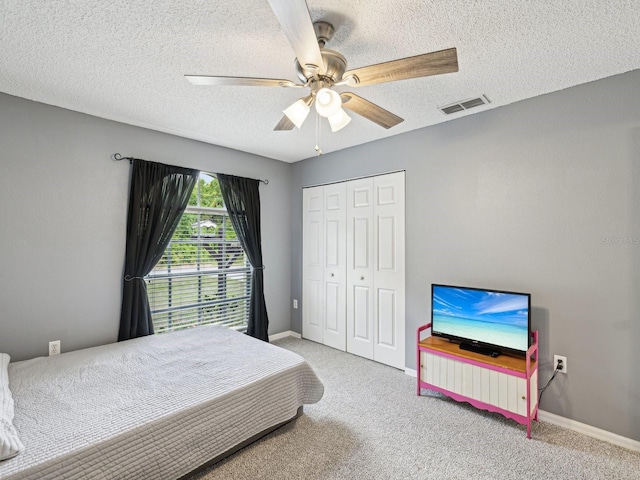 carpeted bedroom featuring a textured ceiling, baseboards, visible vents, and a closet