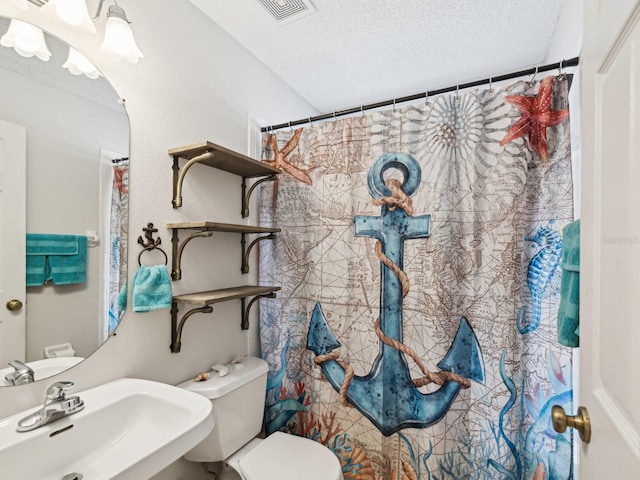 full bathroom featuring toilet, visible vents, a sink, and a textured ceiling