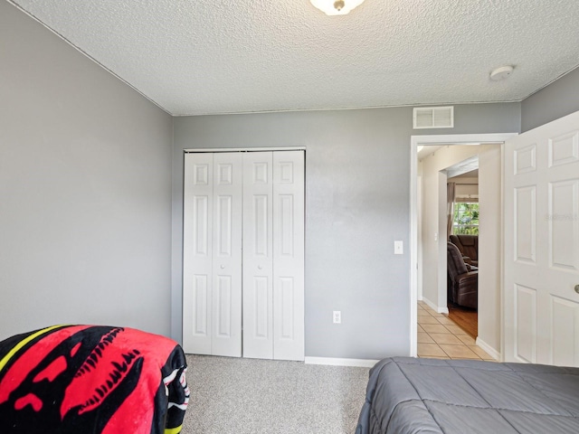 tiled bedroom featuring visible vents, a textured ceiling, and a closet