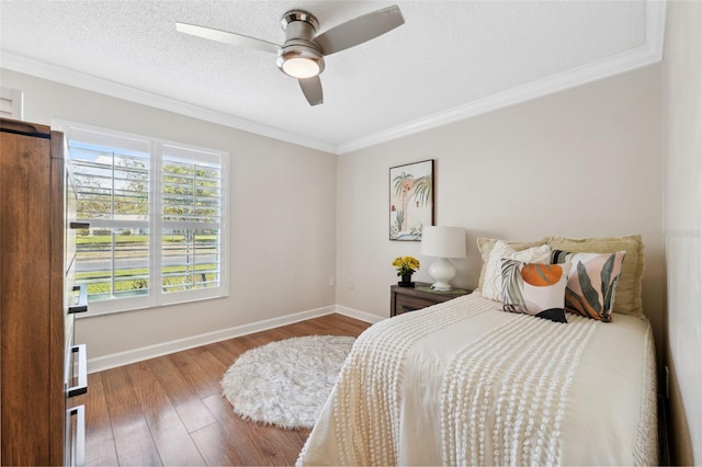bedroom featuring crown molding, baseboards, a ceiling fan, and wood finished floors