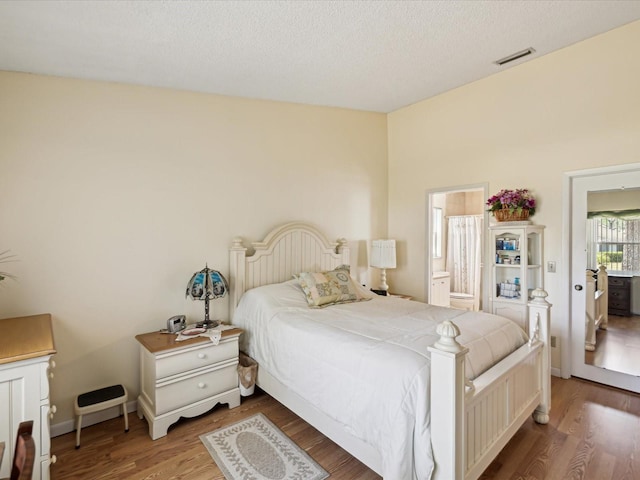 11536 Golden Rain Dr, New Port Richey, FL 34654 - bedroom featuring wood finished floors, ensuite bath, and a textured ceiling