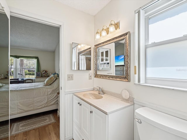 11536 Golden Rain Dr, New Port Richey, FL 34654 - bathroom with connected bathroom, vanity, toilet, wood finished floors, and a textured ceiling