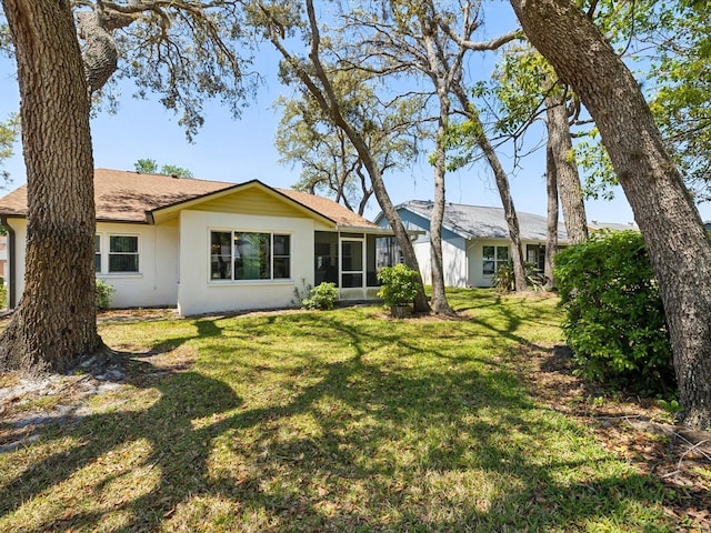 11536 Golden Rain Dr, New Port Richey, FL 34654 - back of house featuring a yard, stucco siding, a sunroom, and roof with shingles