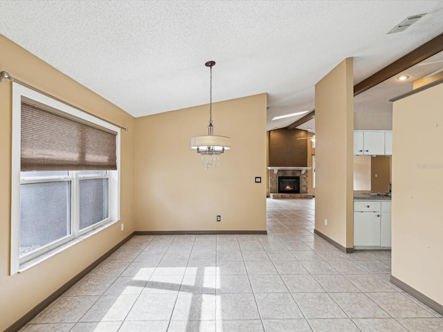 5411 Joyner Ave, Spring Hill, FL 34608 - empty room featuring a textured ceiling, vaulted ceiling, baseboards, a glass covered fireplace, and light tile patterned floors