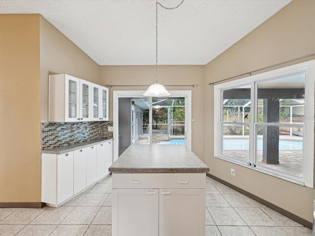 5411 Joyner Ave, Spring Hill, FL 34608 - kitchen with white cabinets, a textured ceiling, light tile patterned flooring, tasteful backsplash, and glass insert cabinets