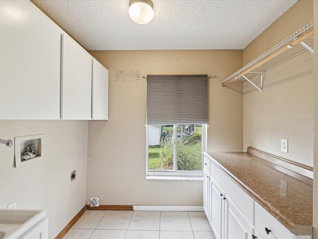 5411 Joyner Ave, Spring Hill, FL 34608 - clothes washing area with a textured ceiling, electric dryer hookup, light tile patterned floors, cabinet space, and washer hookup
