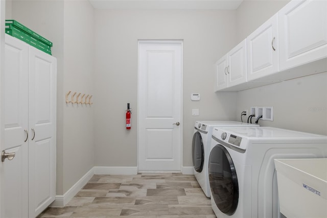 5070 Night Star Trl, Odessa, FL 33556 - laundry area featuring washing machine and dryer, cabinet space, light wood finished floors, and baseboards