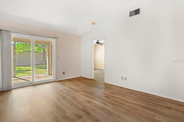 unfurnished room featuring wood finished floors, ceiling fan, baseboards, lofted ceiling, and visible vents
