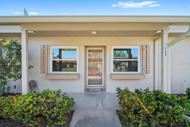 entrance to property with covered porch and stucco siding