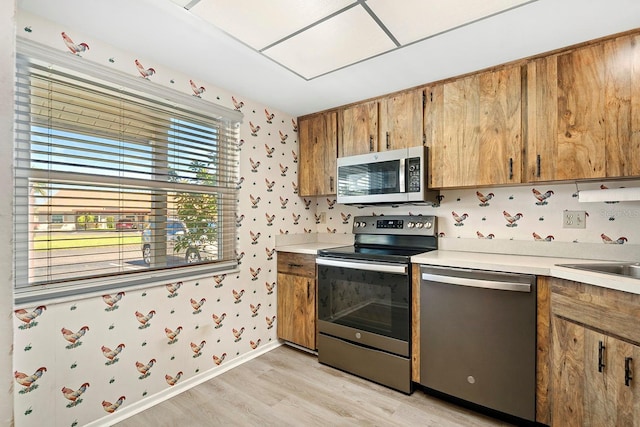kitchen featuring brown cabinetry, light countertops, light wood-style floors, and appliances with stainless steel finishes
