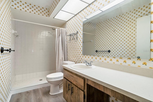 bathroom featuring wallpapered walls, wood finished floors, a tile shower, and toilet