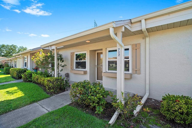property entrance with a yard and stucco siding