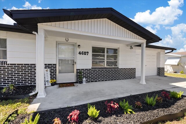4607 Kennedy Dr, New Port Richey, FL 34652 - doorway to property with a porch, driveway, brick siding, and a garage