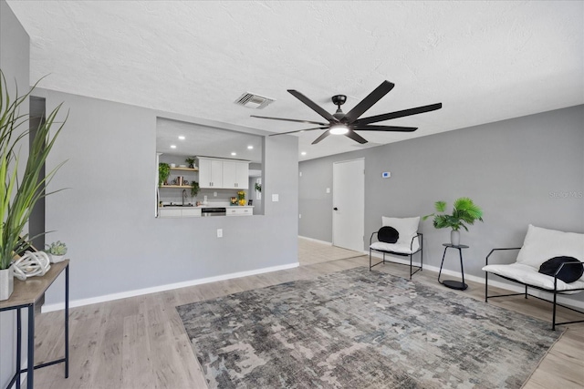 4607 Kennedy Dr, New Port Richey, FL 34652 - living area featuring a textured ceiling, ceiling fan, light wood finished floors, baseboards, and visible vents