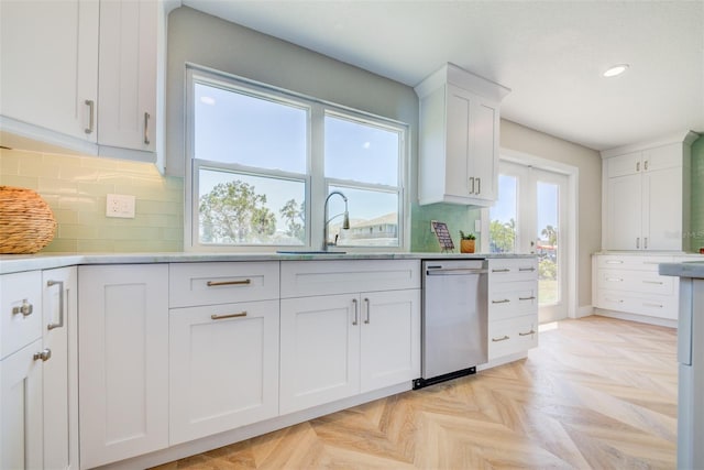 6432 Boatyard Dr, Hudson, FL 34667 - kitchen featuring stainless steel dishwasher, decorative backsplash, light countertops, a sink, and white cabinetry