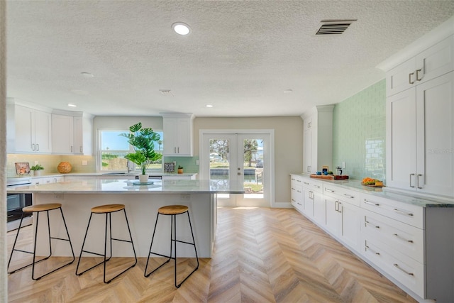 6432 Boatyard Dr, Hudson, FL 34667 - kitchen with a breakfast bar, a textured ceiling, white cabinets, and french doors
