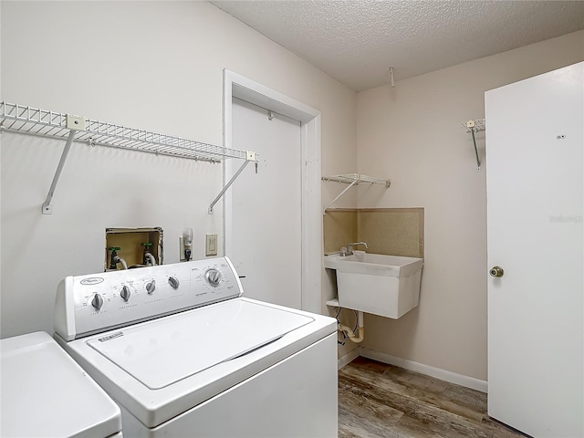 washroom with independent washer and dryer, wood finished floors, a sink, and laundry area