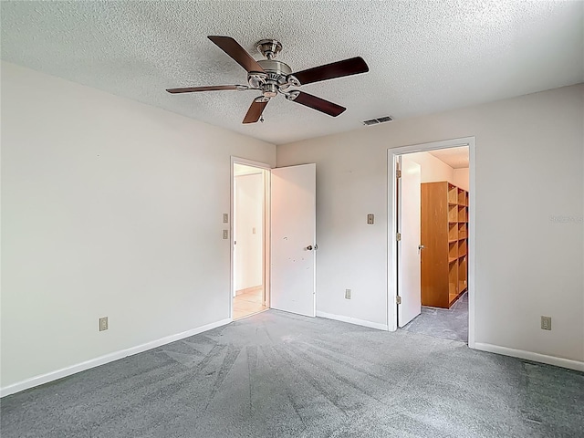 unfurnished bedroom featuring baseboards, carpet flooring, a textured ceiling, and visible vents