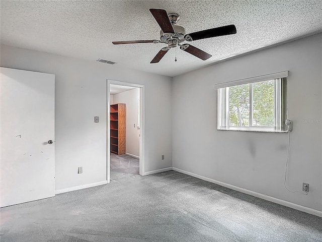 empty room with ceiling fan, a textured ceiling, visible vents, and carpet