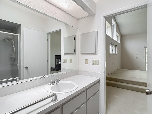 full bath with vanity, a textured ceiling, and a stall shower