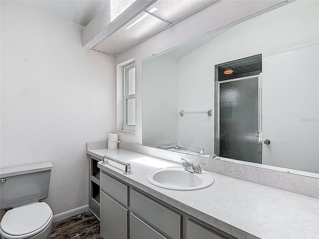 full bathroom featuring wood finished floors, toilet, vanity, baseboards, and a stall shower