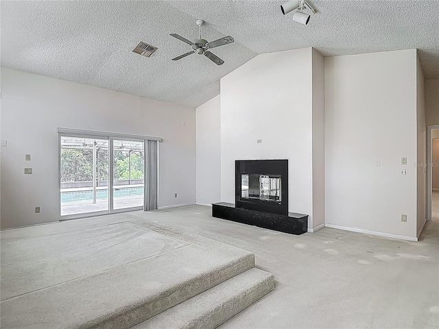 unfurnished living room with visible vents, lofted ceiling, a ceiling fan, a multi sided fireplace, and carpet floors