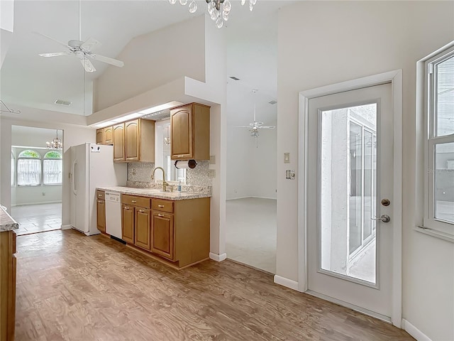 kitchen featuring high vaulted ceiling, ceiling fan with notable chandelier, light wood-style floors, white appliances, and visible vents