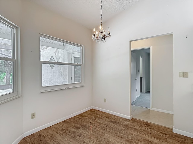 unfurnished room with baseboards, wood finished floors, and a chandelier