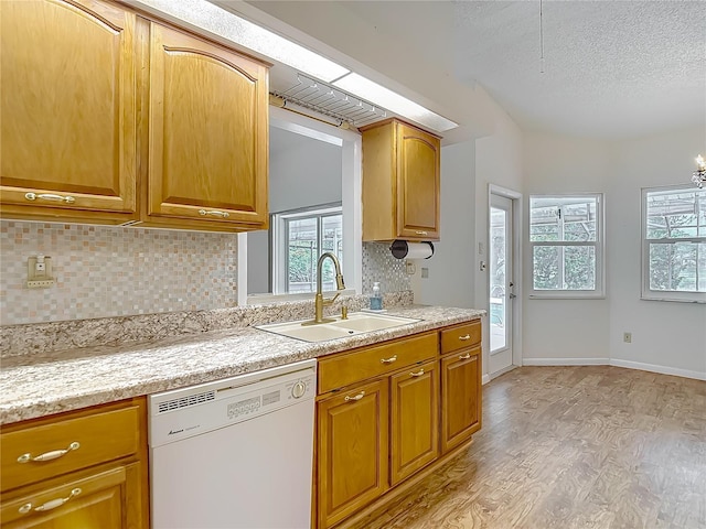 kitchen featuring light wood finished floors, a textured ceiling, a sink, backsplash, and dishwasher