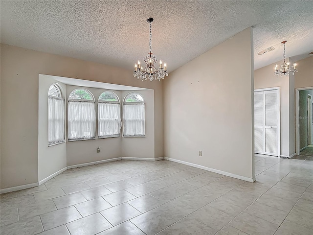 spare room with tile patterned flooring, visible vents, an inviting chandelier, and a textured ceiling