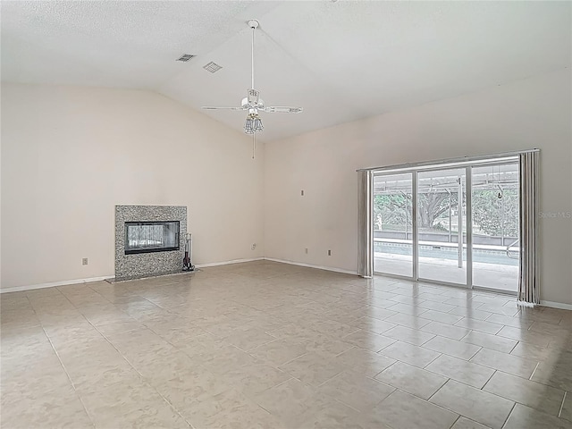 unfurnished living room with lofted ceiling, light tile patterned floors, baseboards, a tiled fireplace, and ceiling fan