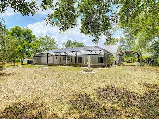 back of property with metal roof, a yard, a lanai, and a carport