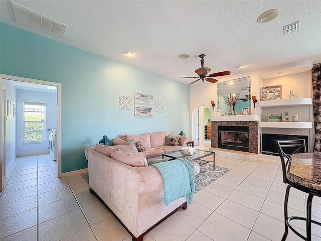 living room with visible vents, a fireplace, light tile patterned flooring, and ceiling fan
