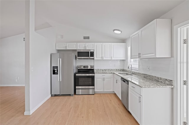 kitchen featuring white cabinets, stainless steel appliances, a sink, visible vents, and light wood-style floors